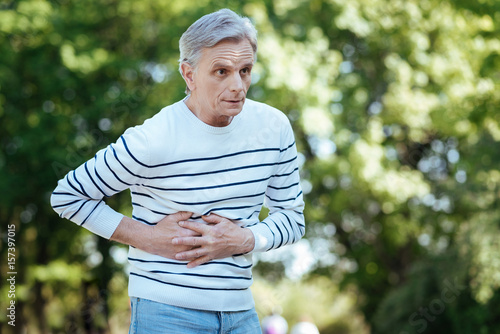 Fototapeta Naklejka Na Ścianę i Meble -  Shocked pensioner having stomachache outdoors