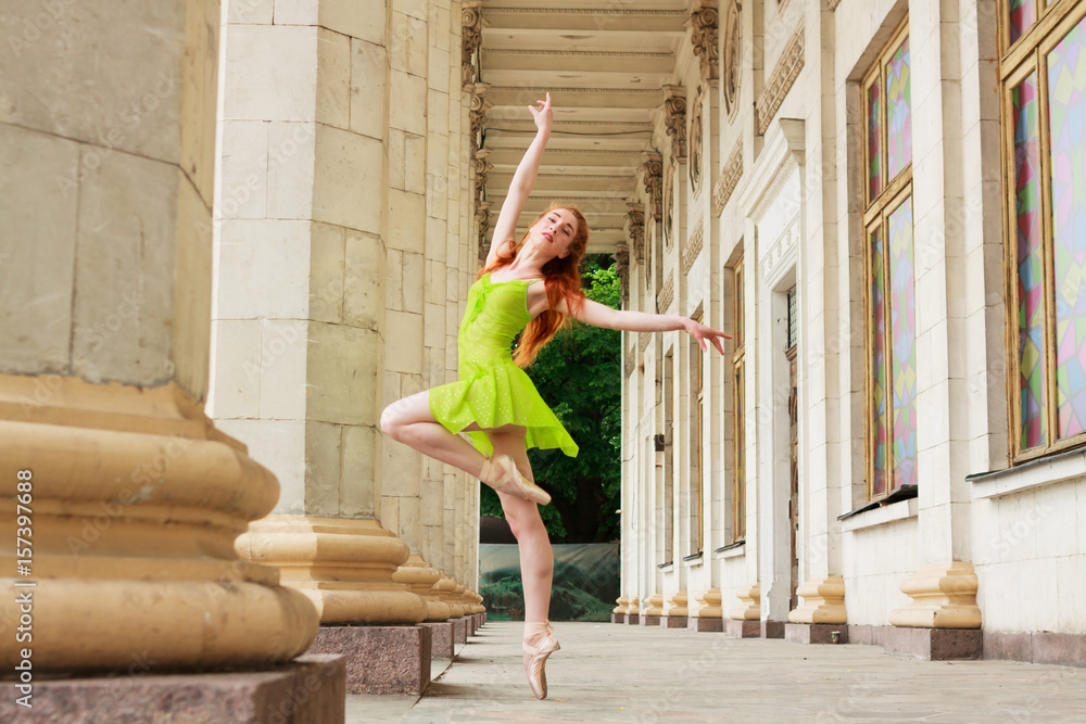 Ballerina dance in a green dress on a background of white columns. ballet dancer posing