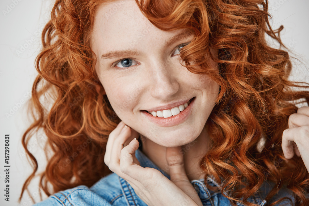 Close up of beautiful natural ginger girl with freckles smiling looking at camera. White background. Close up of beautiful natural ginger girl with freckles smiling looking at camera. White background.