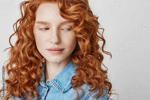 Close up of pretty redhead girl with freckles looking at camera. White background. Copy space.