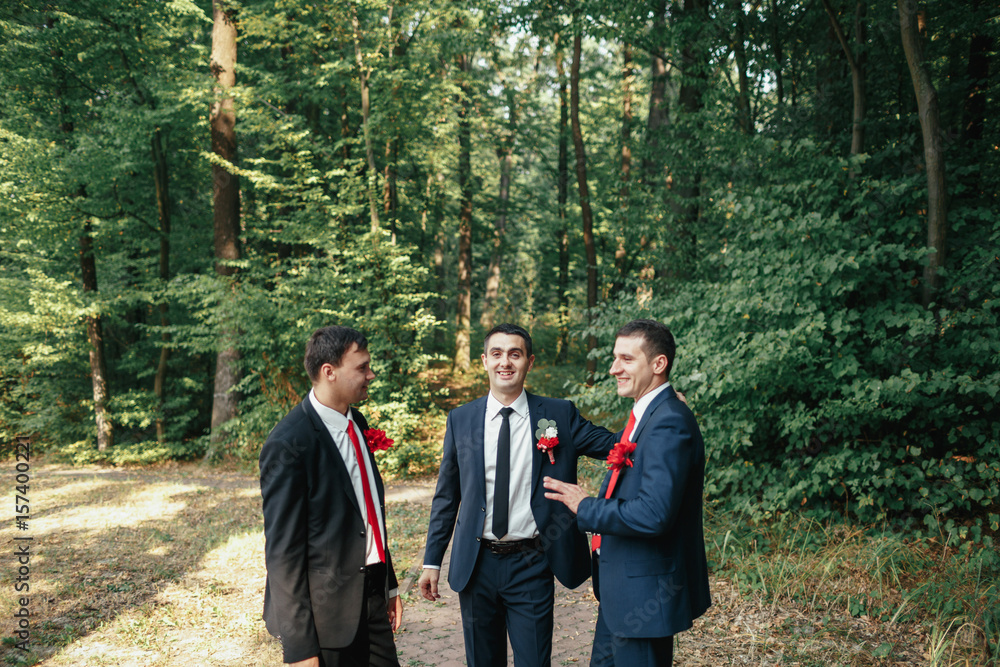 Cheerful groom and groomsmen talk in the forest Cheerful groom and groomsmen talk in the forest