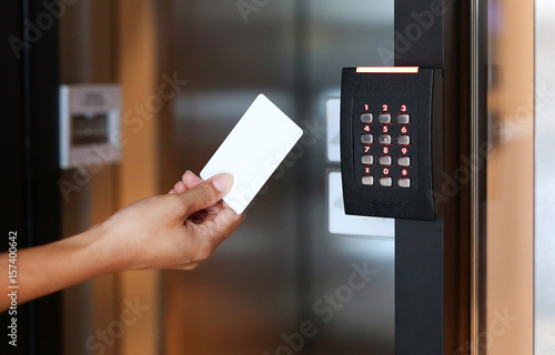 Door access control - young woman holding a key card to lock and unlock door. photo
