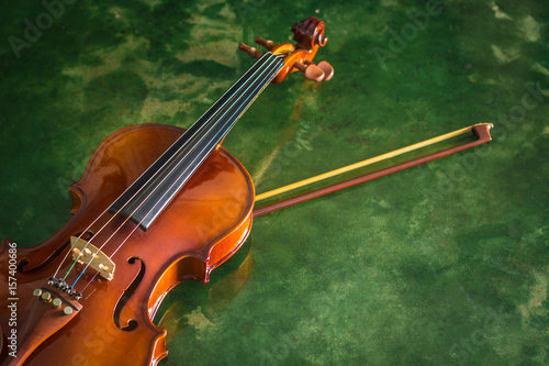 Violin with bow on green cement background