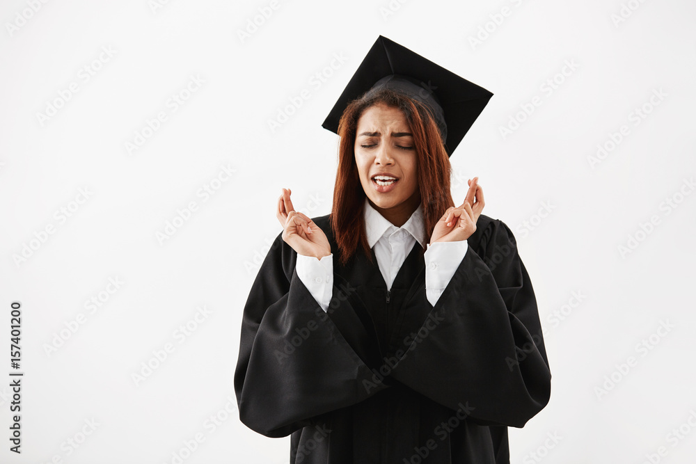African female graduate in black mantle praying over white background. Copy space. African female graduate in black mantle praying over white background. Copy space.