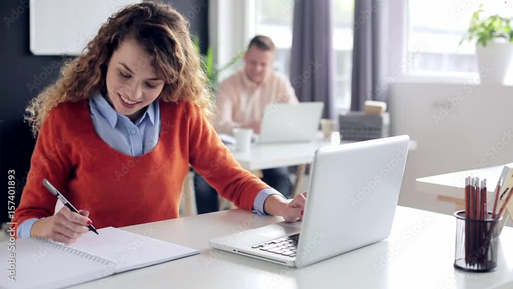 young businesswoman working in modern office sitting at the table with laptop and taking notes young businesswoman working in modern office sitting at the table with laptop and taking notes