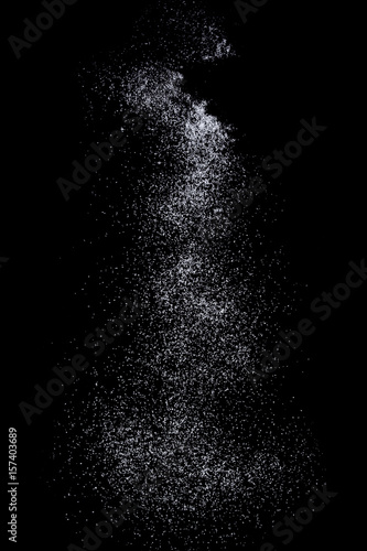Sifting white caster sugar over black background. Isolated