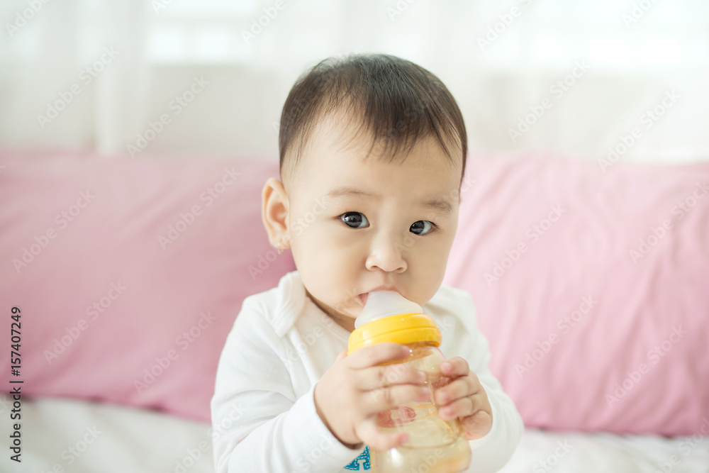 Sweet baby girl sucking milk in bottle at home. Sweet baby girl sucking milk in bottle at home.