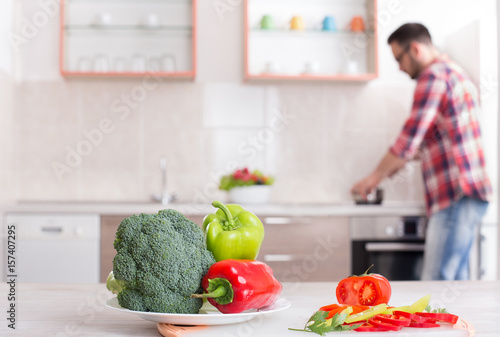 Fresh vegetables on table with man cooking in background