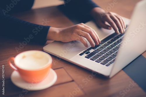 Hand of woman working with her Laptop and Coffee by the side