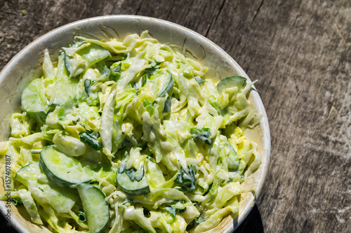 Foto Spring salad with cabbage, cucumber, green onion, parsley and mayonnaise on wood