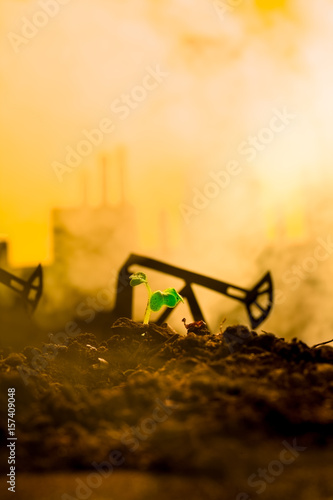 Young green plant in soil on background oil rocking machine