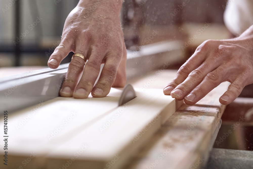 The joiner saws a piece of wood in 2 parts on with electric tool