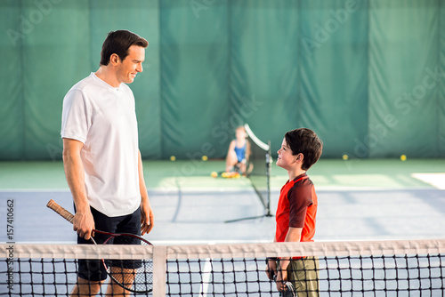 Joyful man playing tennis with his son