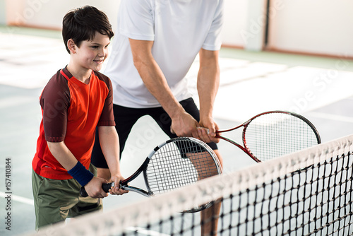 Joyful kid playing tennis with father