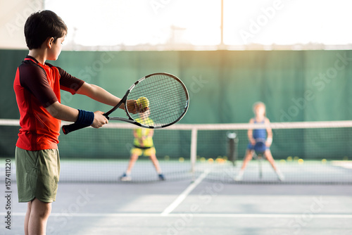 Cheerful kids playing tennis on court © Yakobchuk Olena