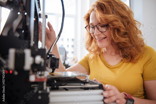 Positive joyful woman checking the work of a 3d printer