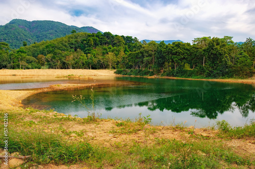 Dense tropical vegetation under the blue sky, Mu Koh Chang National Park, Chang island, Thailand. Mountains covered with various tropical trees and beautiful lake with reflection of nature in water.