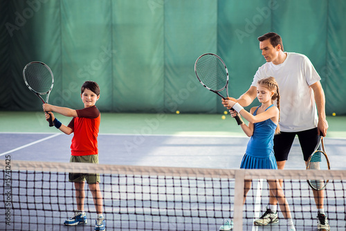 Trainer explaining children how to play tennis