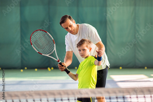 Skillful trainer teaching kid holding racquet