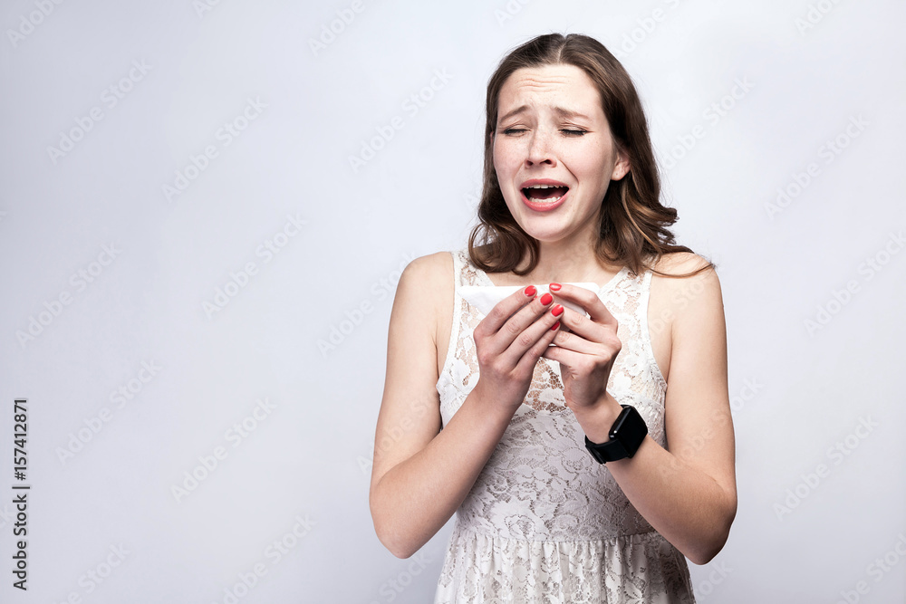 Portrait of sick cold woman with freckles and white dress and smart watch on silver gray background. healthcare and medicine concept. Portrait of sick cold woman with freckles and white dress and smart watch on silver gray background. healthcare and medicine concept.
