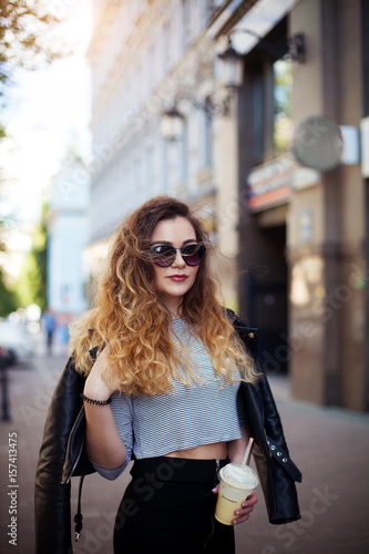 Close up fashion street style portrait of a beautiful girl in a casual outfit walks in the city .