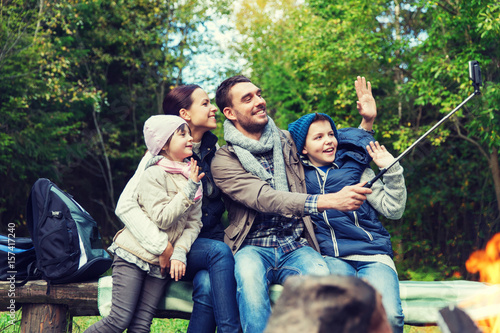 family with smartphone taking selfie near campfire
