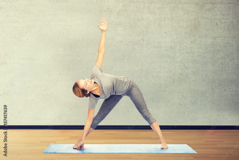 woman making yoga triangle pose on mat