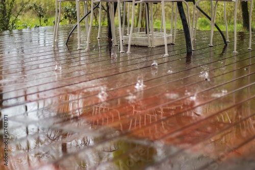 reflection of whait chairs at raining drops on wooden outside fl photo