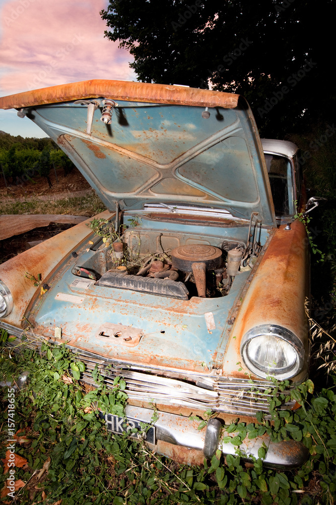 capot ouvert d'une vieille voiture abandonnée dans les herbes