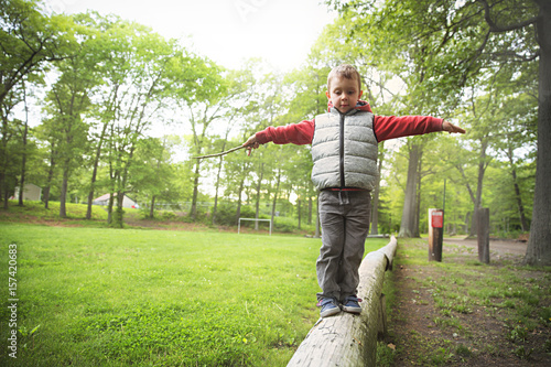 Little boy walking on a log in the park.  child on the balance beam. Copy space for your text photo