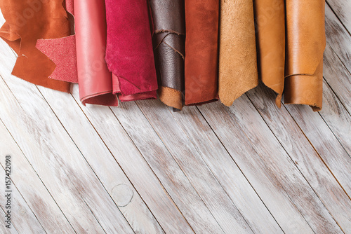 Multicolored leather in rolls on wooden background. photo