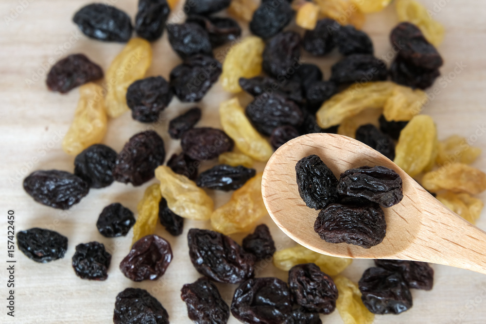 Dried raisins in wooden spoon on wood table. Dried raisins in wooden spoon on wood table.