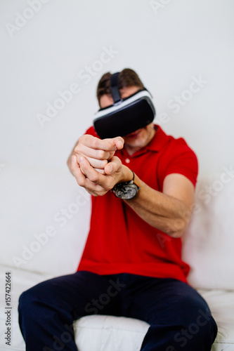 Young man wearing virtual reality goggles and playing video game.