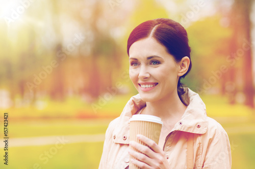 smiling woman drinking coffee in park