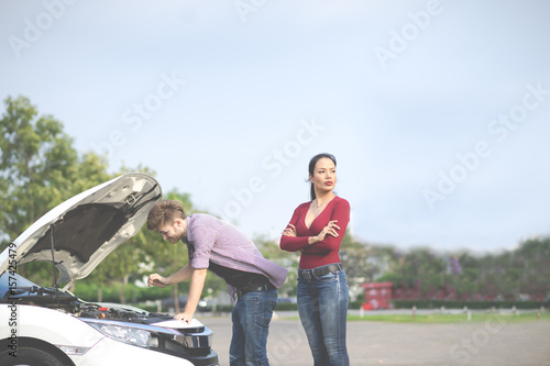 A couple has engine failure car breakdown, Woman feeling angry frustrated suffering. Man try to fix engine.