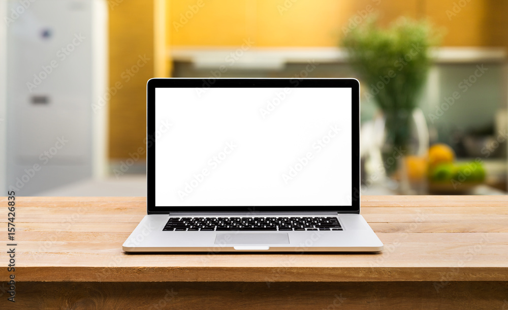 Fototapeta premium Modern computer,laptop with blank screen on wooden table with blur kitchen background