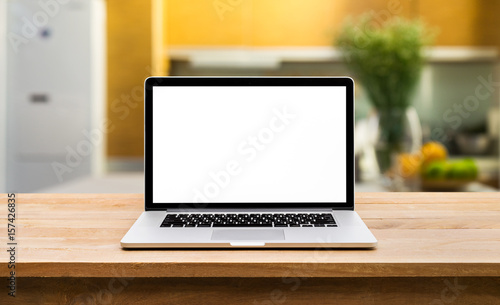 Fototapeta Naklejka Na Ścianę i Meble -  Modern computer,laptop with blank screen on wooden table with blur kitchen background