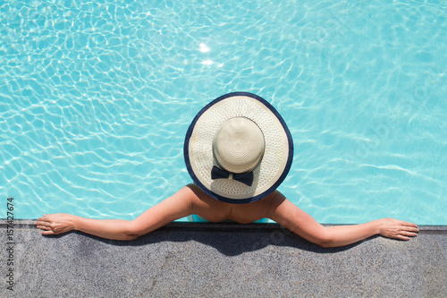 Beautiful woman sunbathing by the pool top view. Summer background.