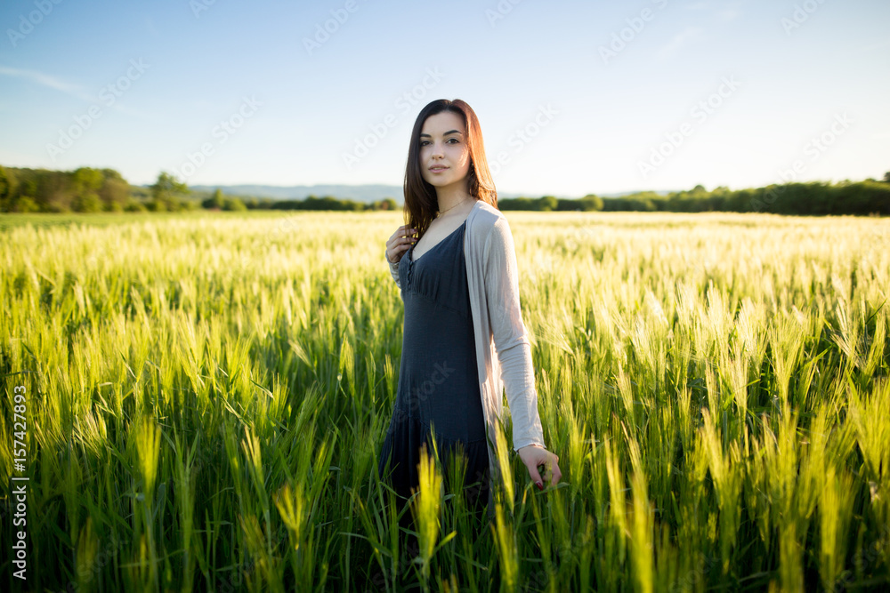 Beautiful carefree woman in fields. Beautiful brunette lady in wheat field at sunset Beautiful carefree woman in fields. Beautiful brunette lady in wheat field at sunset