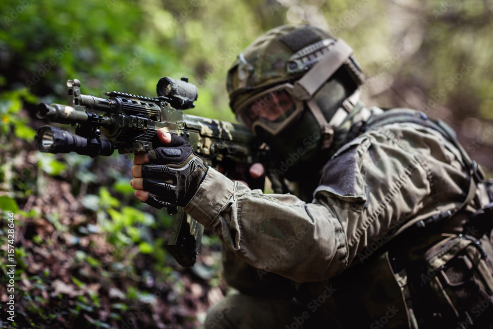 Fototapeta premium Soldier takes aim in forest