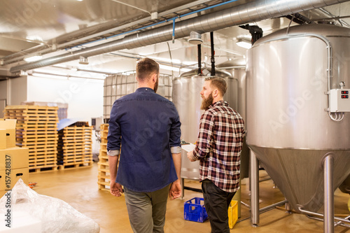 men with clipboard at craft brewery or beer plant