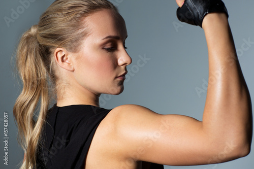 close up of woman posing and showing biceps in gym