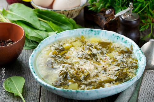 Fotografie Simple vegetarian soup made of sorrel, potatoes and beaten eggs on a light background