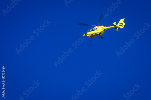 Yellow helicopter on clear dark blue sky
