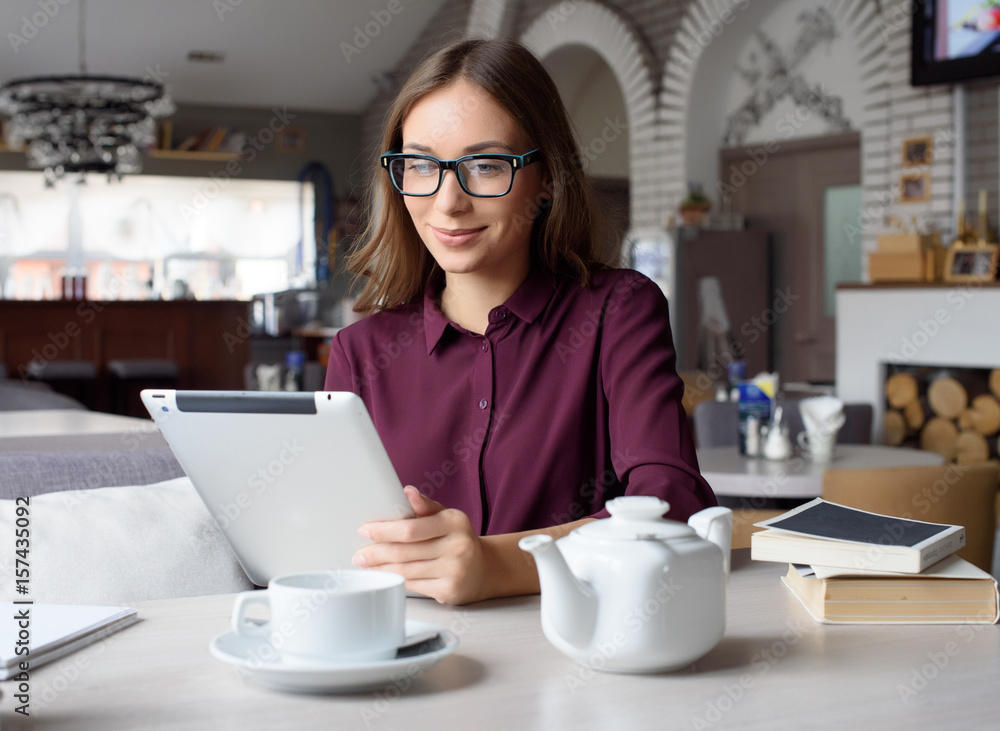 Concentrated at work. Confident young woman in smart casual wear working on laptop while sitting near window in creative office or cafe Concentrated at work. Confident young woman in smart casual wear working on laptop while sitting near window in creative office or cafe
