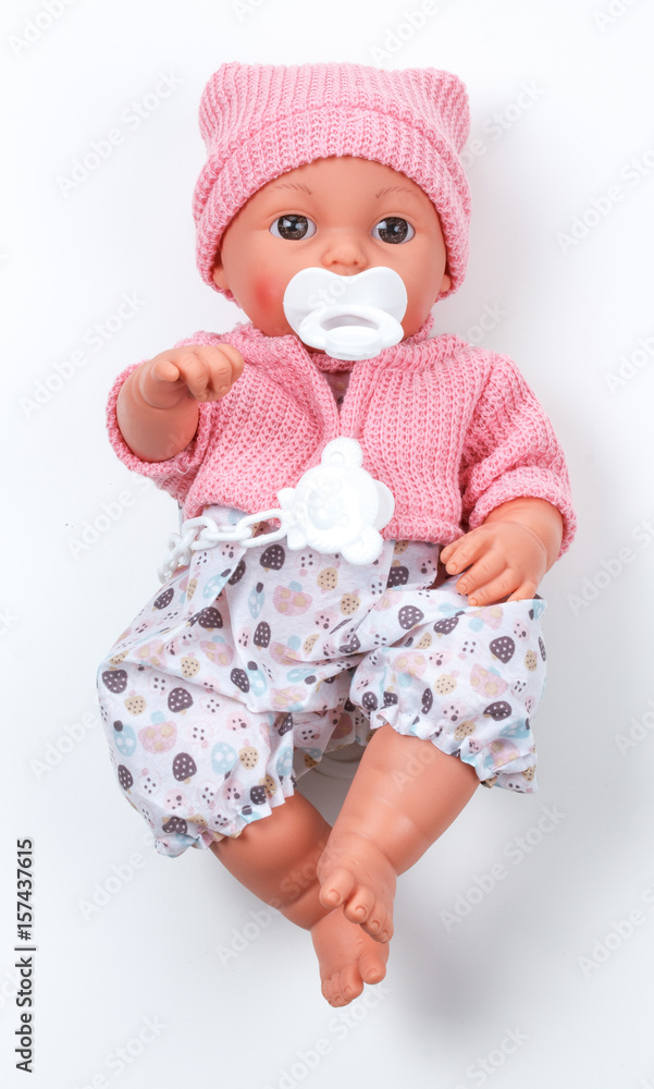 Toy doll child, in pink blouse with pacifier on isolated background Toy doll child, in pink blouse with pacifier on isolated background