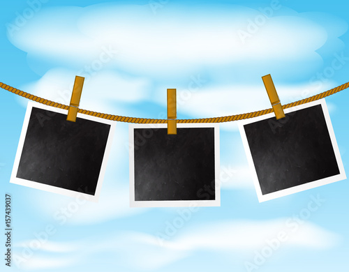 Set of blank photo frames hanging on the rope with wood pins on sky background
