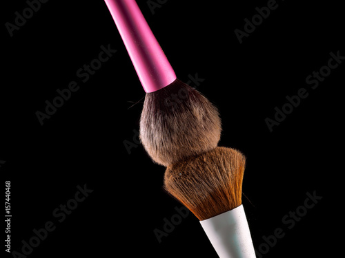 Cosmetic makeup brushes on  black background flash explosion splash powder shadow blush.