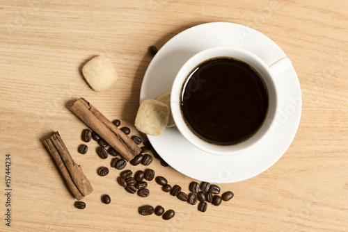 Black coffee in a cup and saucer with cinnamon sticks and coffee beans 