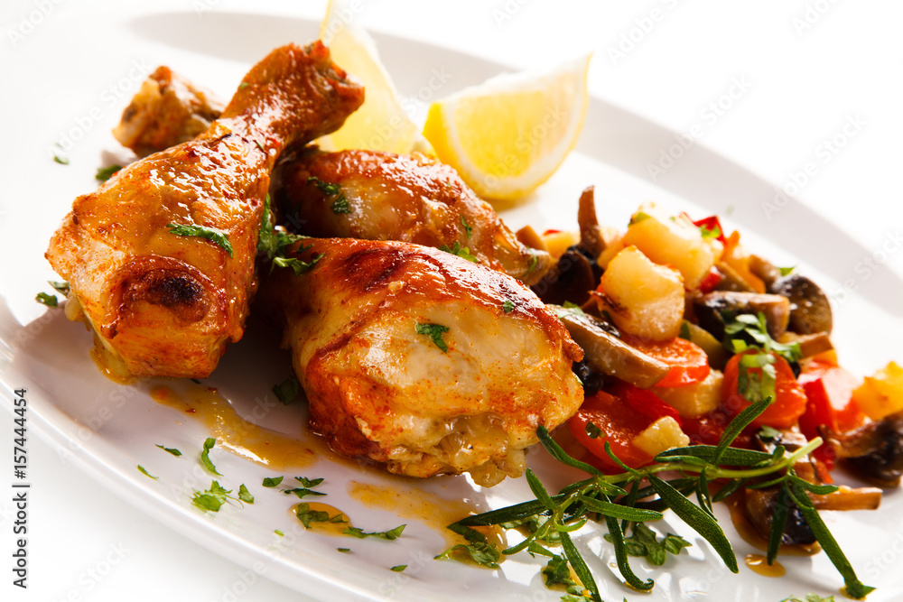Grilled chicken drumsticks with vegetables on white background Grilled chicken drumsticks with vegetables on white background